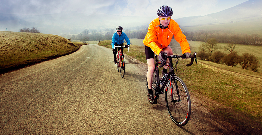 Two Cyclists Climbing Road